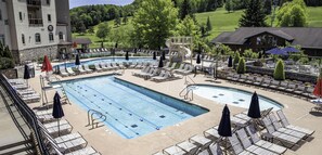 Un espace piscine avec des chaises longues, un toboggan et une vue sur un paysage verdoyant.