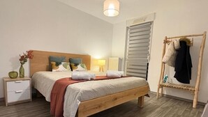 Ein Schlafzimmer mit einem hölzernen Bett, einem Nachttisch, einer Lampe, einem Heizkörper und einem Kleiderständer.