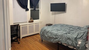 A bedroom with a bed, a window with curtains, a ceiling fan, a TV mounted on the wall, and a small table. - 2bedroom, No living room, EinsteinHospital & Salus University (Philadelphia)
