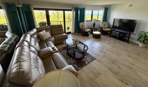 Een woonkamer met een leren modulaire bank, een glazen salontafel en een flatscreen televisie.