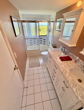 Een badkamer met twee wasbakken, een badkuip en een douche.