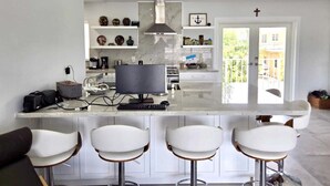 A modern kitchen with a central island, bar stools, and a view of the outside. - Sunset, Waterfront Key Largo House, with a 100' Boat Dock (Key Largo)
