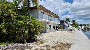 A beachfront property with a two-story building, a covered patio, and a boat dock. - Sunset, Waterfront Key Largo House, with a 100' Boat Dock (Key Largo)