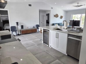 A modern kitchen with a marble countertop, white cabinetry, and a built-in dishwasher. - Sunset, Waterfront Key Largo House, with a 100' Boat Dock (Key Largo)