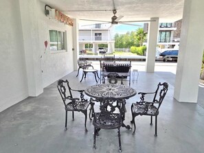 A covered patio with a round table and four chairs, a ceiling fan, and a sign that reads "LIQUORS". - Sunset, Waterfront Key Largo House, with a 100' Boat Dock (Key Largo)