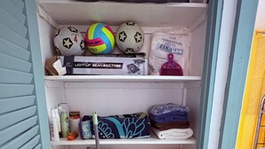 Ein Lagerraum mit Regalen, der verschiedene Gegenstände wie einen Fußball, ein Moskitonetz und Reinigungsmittel enthält.
