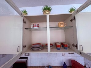 Une cuisine avec des meubles blancs, une étagère en verre et un pare-feu en carrelage.