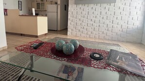 Ein Wohnzimmer mit einem Glastisch, einem roten und blauen Dekorationsgegenstand, einer Fernbedienung und einer Zeitschrift.