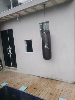 A room with a wooden floor, a black punching bag, a window, and a door.