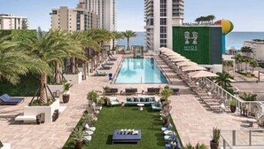 A rooftop pool area with lounge chairs, a small lawn, and a view of the ocean. - 3BR Oceanview HYDE – Free Parking, No Resort Fees (Hollywood)