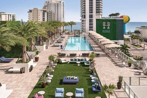 A rooftop pool area with lounge chairs, a small lawn, and a view of the ocean. - 3BR Oceanview HYDE – Free Parking, No Resort Fees (Hollywood)