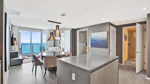 A modern hotel room with a large island in the center, a dining area with a view of the ocean, and a spacious living area with large windows. - 3BR Oceanview HYDE – Free Parking, No Resort Fees (Hollywood)