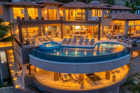 A multi-level resort with a large outdoor swimming pool, sun loungers, and a dining area.