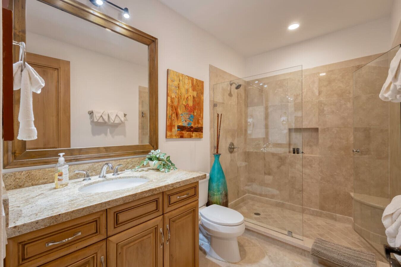 Un baño moderno con un espejo grande, un lavamanos, un inodoro y una ducha a ras de suelo.