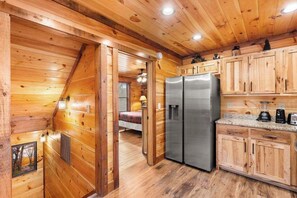 A wooden cabin interior with a kitchen, a bedroom with a bed, and a bathroom with a shower. - Quiet 3BR - Near downtown - HotTub Arcade Theater (Gatlinburg)