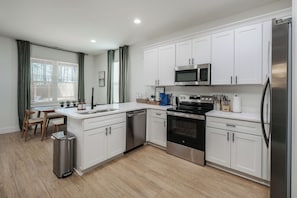 A modern kitchen with white cabinets, stainless steel appliances, a dishwasher, and a trash can. - NEW Family& Pet Friendly, 65" TV, Fire Pit, WD (Boiling Springs)