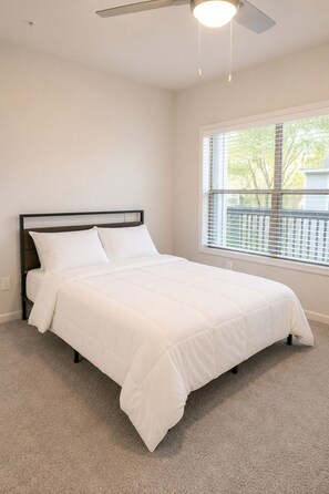 A bedroom with a bed, a ceiling fan, a window with blinds, and a carpeted floor. - FIFA World Cup 2026! Modern 2BR · Pool, Gym & MARTA Access (Atlanta)
