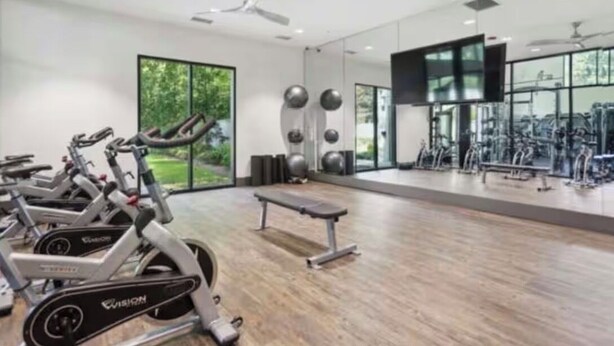 Een sportschool met hometrainers, een bank en fitnessapparatuur.