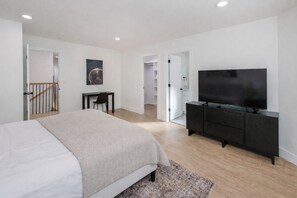 A modern bedroom with a bed, a TV, a desk, and a staircase leading to another room. - NEW MODERN 1500 SQ FT RETREAT, 65” TV, Fire Pit, Family & Pet Friendly, Sleeps 6 (Boiling Springs)