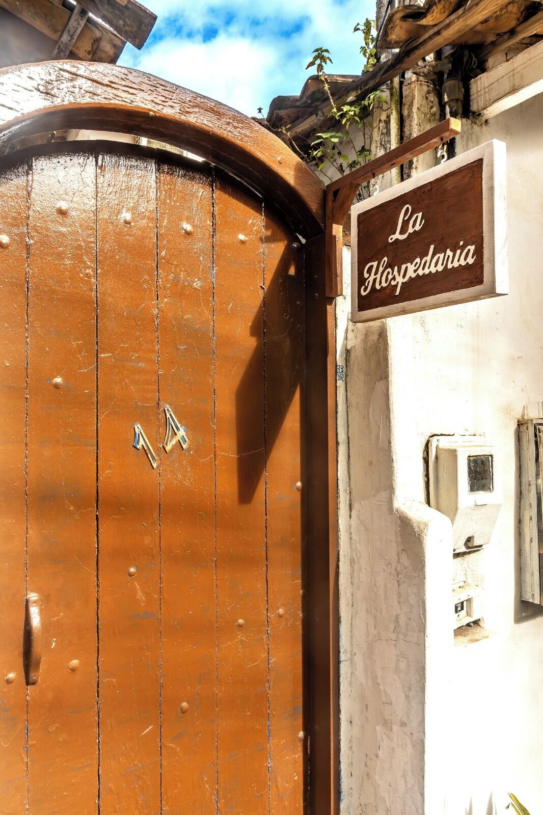 Um portão de madeira com uma placa que diz "La Hospedaria" e o número 14.