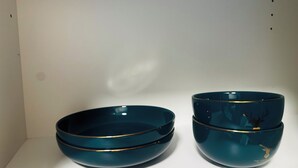 Dos cuencos azul oscuro con detalles dorados sobre un estante blanco.