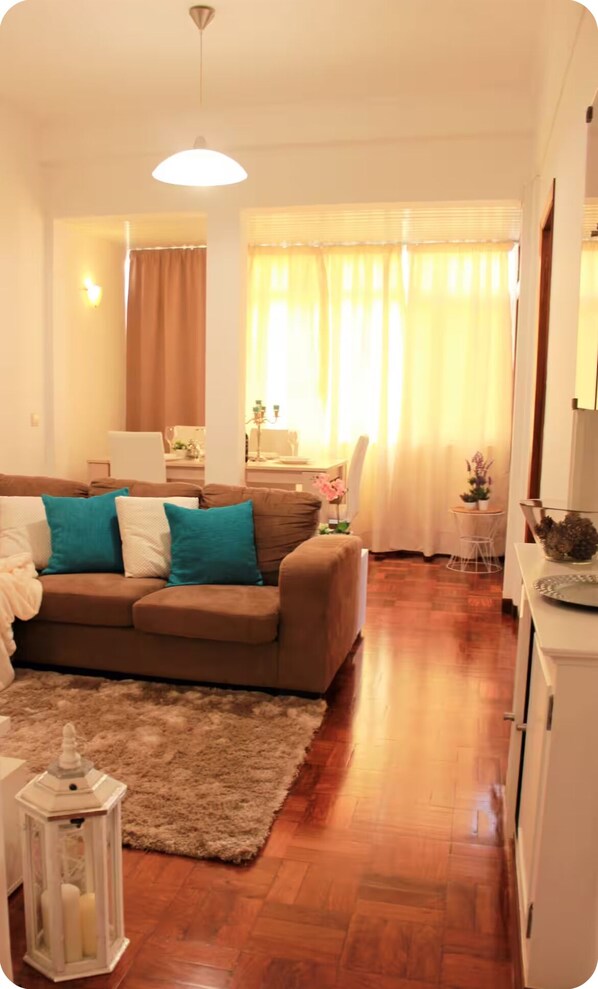 Ein gemütliches Wohnzimmer mit einem braunen Sofa, einer weißen Kommode und einem kleinen Tisch mit einer Pflanze.