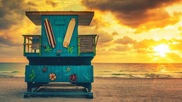 A lifeguard tower with a surfboard, beach warning flags, and a sunset view. - Stylish & Centrally Located Miami Stay / Free Parking & Fast WiFi (Miami)