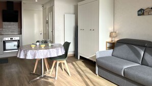 Ein kompakter Wohnbereich mit Essplatz, Küchenzeile und grauem Sofa.