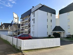 A multi-story building with a white facade and a red car parked in front. - Le P’tit Pilours - Saint Gilles Croix de Vie (SAINT GILLES CROIX DE VIE)