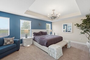 Un dormitorio con cama, mesitas de noche, cómoda, banco, candelabro y planta en maceta.