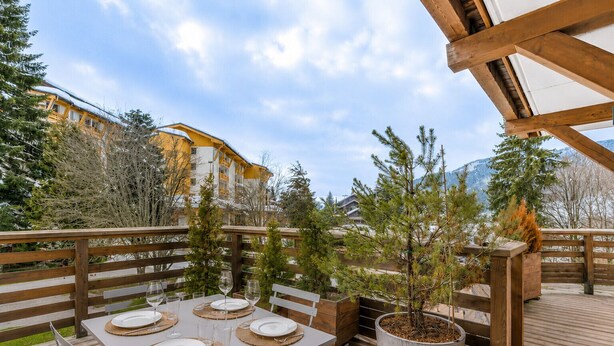 An outdoor dining area with tables set for four, surrounded by wooden railings and potted plants. - Rochebrune Ski Terrace - Welkeys (Megève)