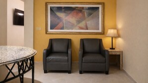 A room with two black leather chairs, a round marble table, a framed abstract painting, a lamp, and a television on the wall. - Motel Virreyes  (Mexicali)