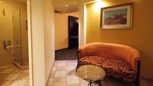 A hotel room with a shower, a sofa, a small round table, and a painting on the wall. - Motel Virreyes  (Mexicali)
