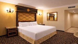 A hotel room with a large bed, a nightstand, a bedside table, a wall-mounted lamp, and a mirror. - Motel Virreyes  (Mexicali)