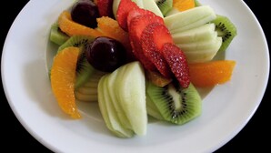 A plate of assorted fresh fruits including strawberries, kiwi, oranges, and grapes. - Motel Virreyes  (Mexicali)