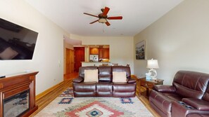 A living room with a brown leather sofa, a television, a fireplace, and a ceiling fan. - Ground Floor | Fireplace | Master en-suite | Grande 116 (Angel Fire)