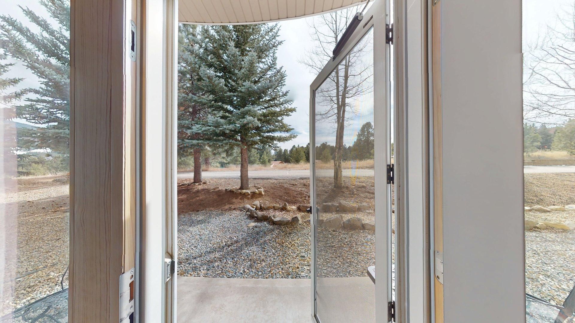 A doorway leading to an outdoor area with a gravel path, a tree, and a clear sky.