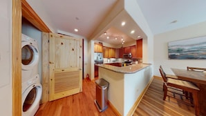 Una cocina compacta con armarios de madera, un refrigerador de acero inoxidable y una encimera de granito.