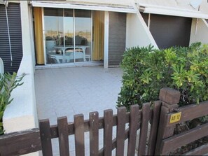Ein Wohnhaus mit einer Terrassenfläche, einer Schiebetür, die zu einem Essbereich führt, und einem Holzzaun mit einem Schild.