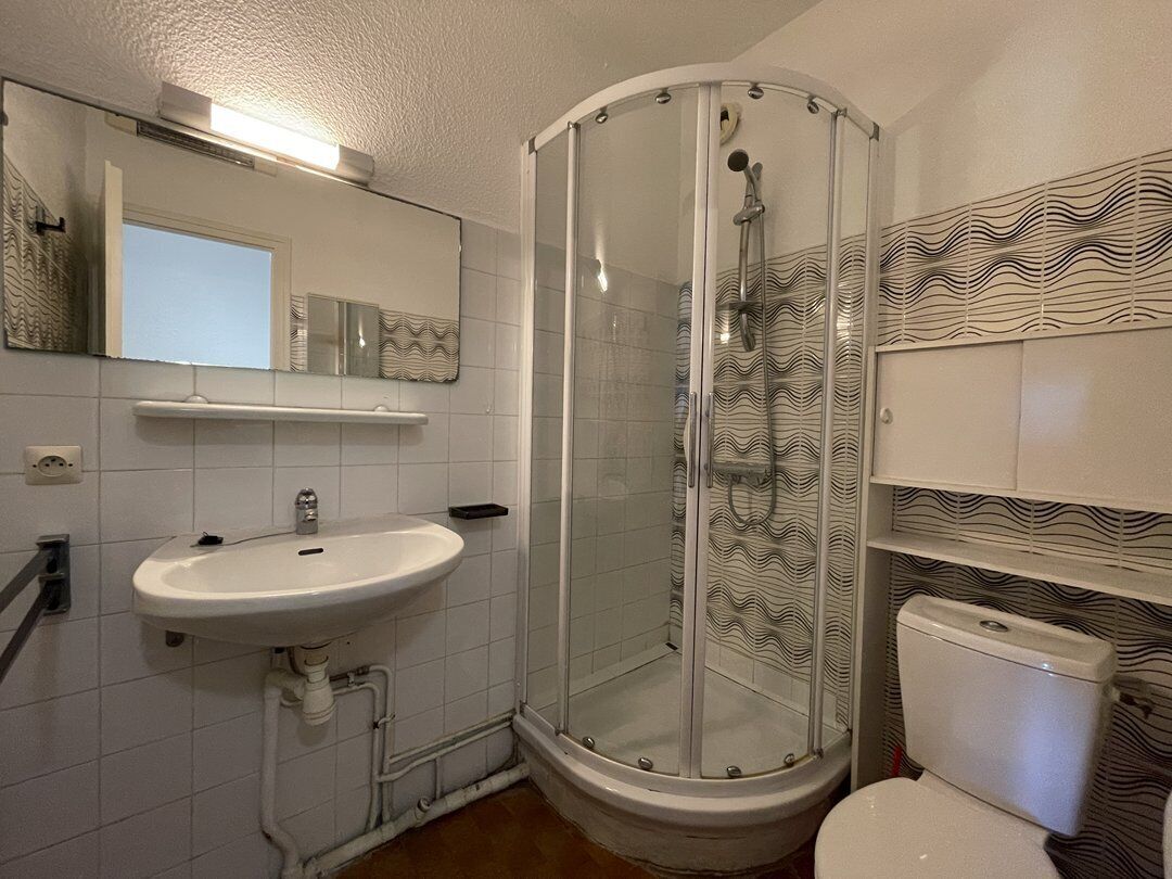 A bathroom with a glass-enclosed shower, a sink, and a toilet.