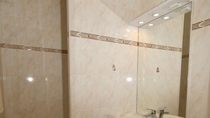 Ein Badezimmer mit Dusche, Waschbecken und Spiegel.