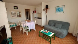 Ein kompakter Wohnbereich mit Essplatz, einer Couch, einem kleinen Tisch und einer Küchenzeile.