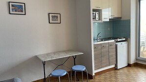 Uma cozinha compacta com bancada, pia e máquina de lavar louça. Há uma pequena mesa com dois banquinhos.