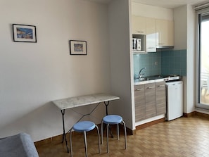 A compact kitchen with a countertop, sink, and a dishwasher. There is a small table with two stools. - Studio Héliopolis AB242 - 4 people (AGDE)