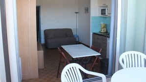 Um espaço compacto com mesa de jantar, cadeiras, sofá e cozinha compacta.
