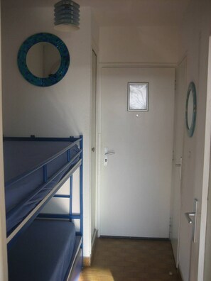 A room with bunk beds, a door with a small window, and a wall-mounted mirror. - Studio Héliopolis AB305 - 4 people (AGDE)