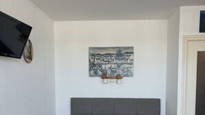 Una camera da letto con un letto, una televisione a parete, un quadro e una porta.