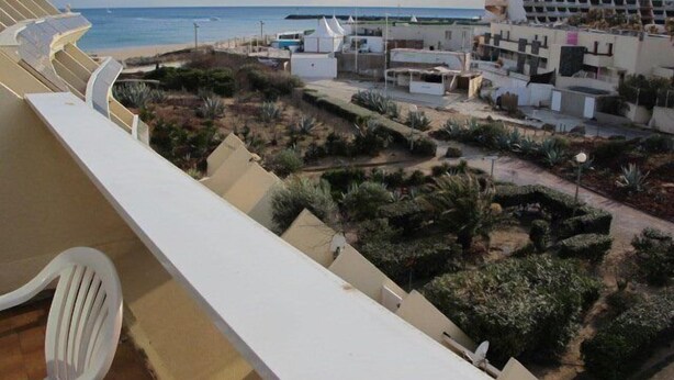 Un hotel sul lungomare con un balcone affacciato sulla spiaggia e sull'oceano.