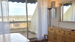 Un balcone con tavolo e sedie in legno, un armadietto in legno e vista sulla città.