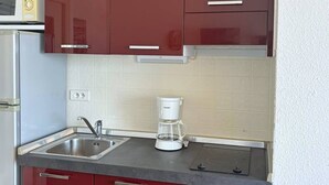 Una cucina con mobili rossi, un lavandino in acciaio inossidabile e una macchina per il caffè.